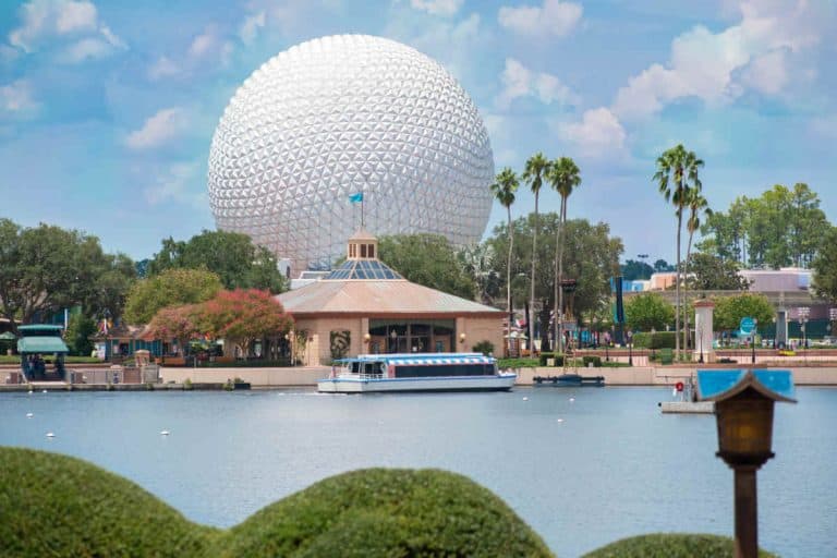 Back view of the Epcot ball in the distance with the lagoon in the front along with a friendship boat at the docks