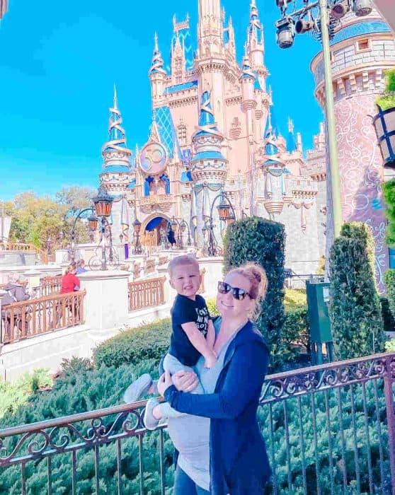 Pregnant at Disney World holding toddler in front of castle