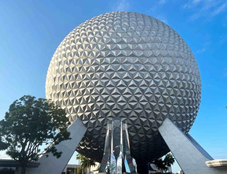 Iconic symbol of Epcot, the Epcot Ball, held up by steel beams on a blue sky day