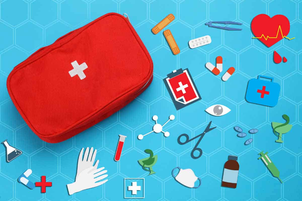 blue background with several first aid items such as band aids, scissors, tweezers and medicine outside of a first aid bag